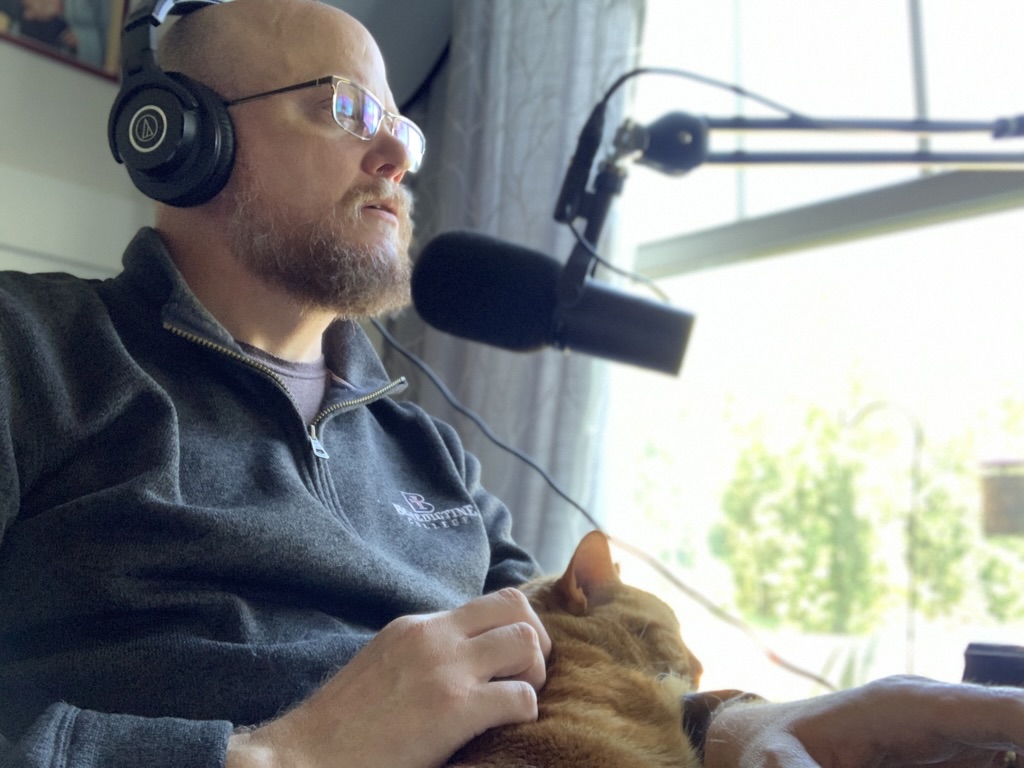 Greg Willits narrating an audiobook with his cat nearby